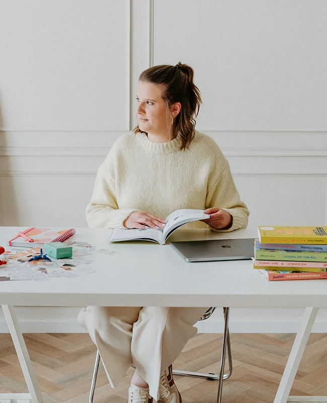 Joyce schaut aus dem Fenster mit Fachliteratur vor sich liegend rund um die Themen Sexualpädagogik